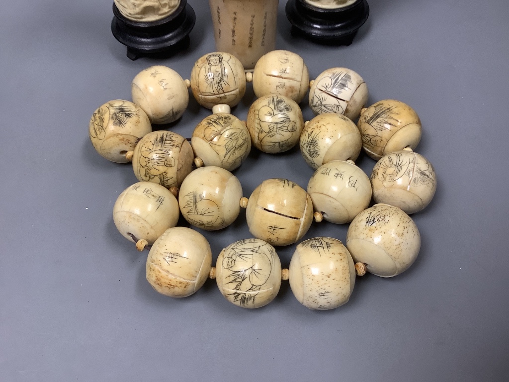 A Chinese engraved bone bead necklace, a pair of engraved bone vases on stands and an engraved bone dice shaker